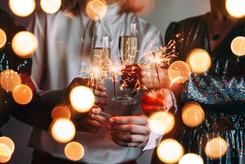 people holding sparklers and glasses of champagne toasting