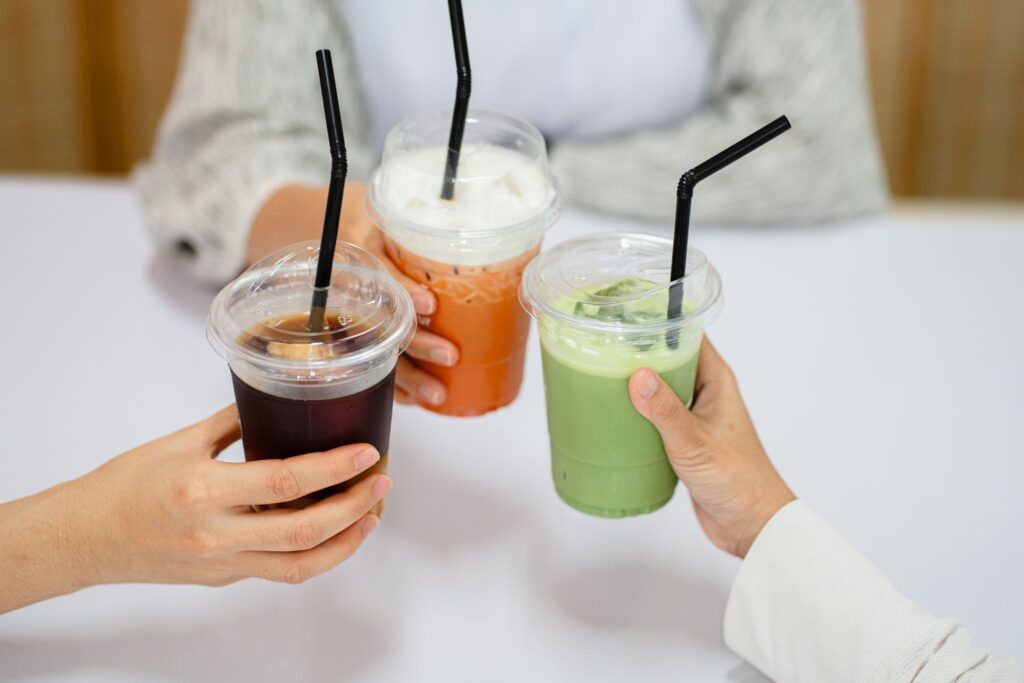 A variety of drinks being cheers in plastic cups