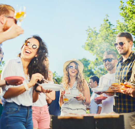 Small,Group,Of,People,Standing,Around,Barbecue,Grill,At,Outdoor